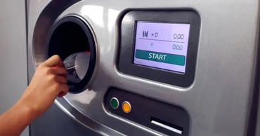 person inserting empty plastic bottle into bottle deposit machine