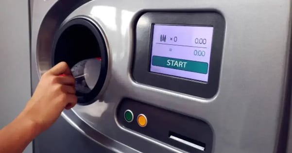 person inserting empty plastic bottle into bottle deposit machine