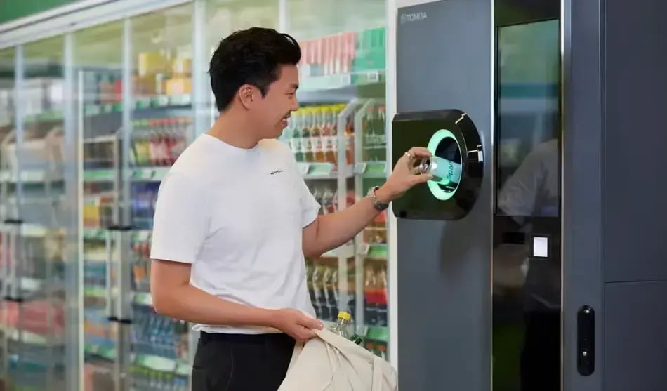 Man placing empty cans into a reverse vending machine for bottle deposit returns