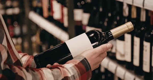 someone holding a wine bottle in a wine shop