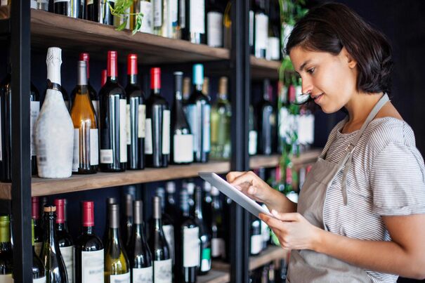 Woman on tablet in liquor store with wine