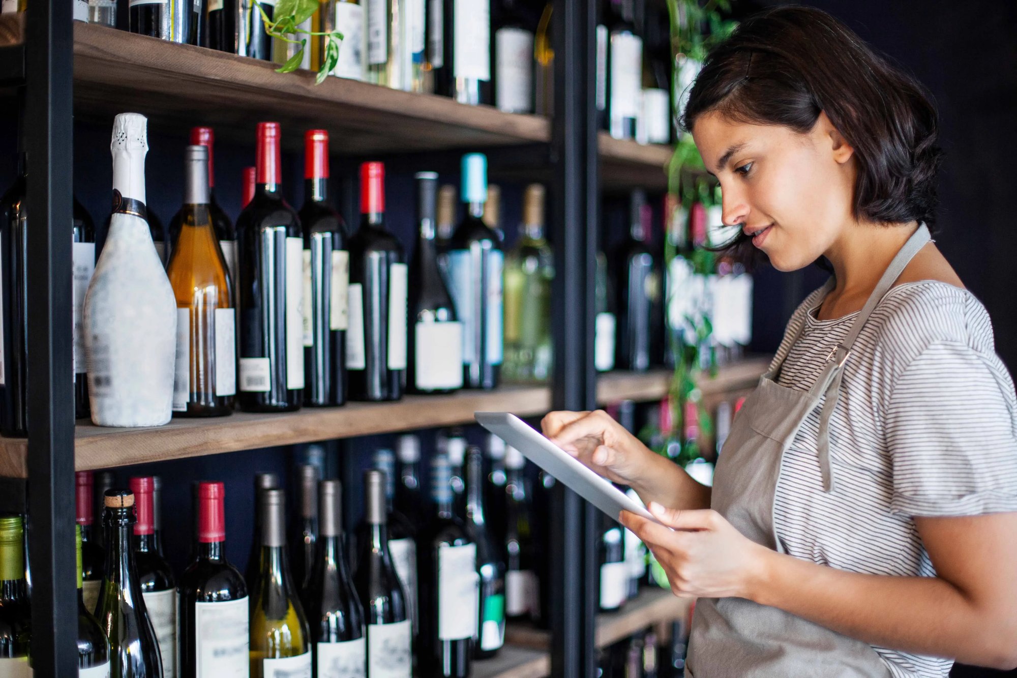 woman on tablet in liquor store with wine